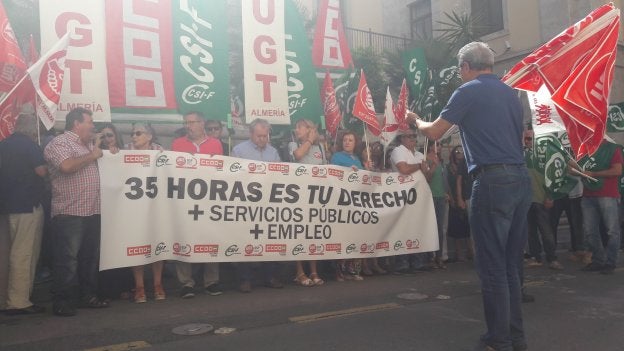 Uno de los manifestantes, que porta unas banderas de UGT, organiza al resto de grupos sindicales que sostienen una pancarta.