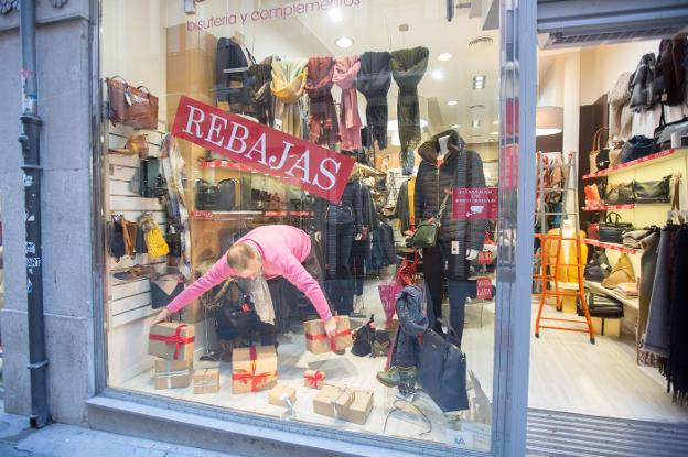 Enrique Muñoz aprovechó la mañana de ayer para retirar los adornos navideños y colgar el cartel de rebajas en su escaparate de la calle Zacatín./ALFREDO AGUILAR