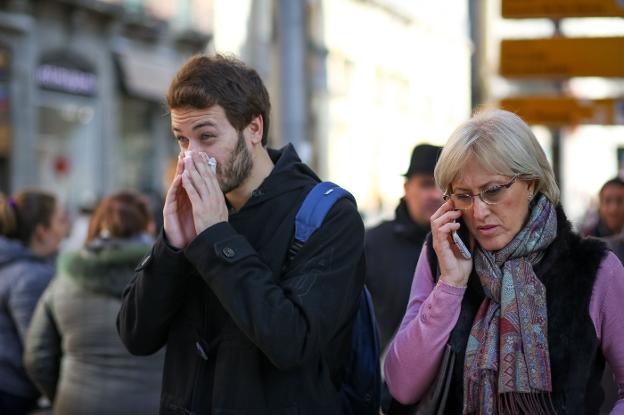 Un joven se suena la nariz mientras camina por la calle./IDEAL