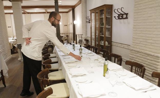 Un camarero dispone elementos sobre una de la mesas del restaurante. /J.M.